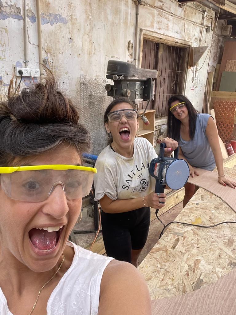 Team members cutting and sanding wooden parts in the workshop